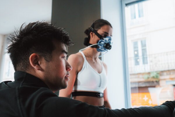 coach qui lance un test de vo2 max sur tapis pour une femme qui porte un masque d'analyse