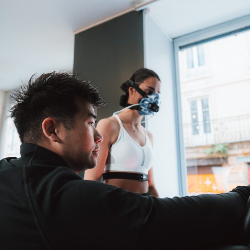 coach qui lance un test de vo2 max sur tapis pour une femme qui porte un masque d'analyse
